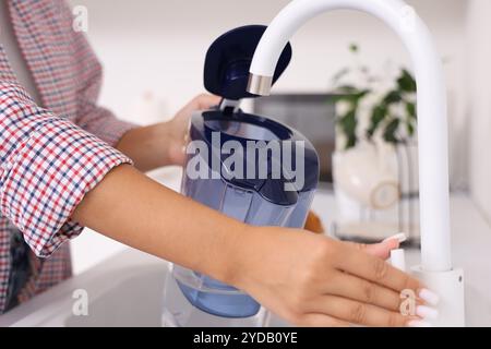 Junge Frau, die Wasserfilterkrug in der Küche füllt, Nahaufnahme Stockfoto