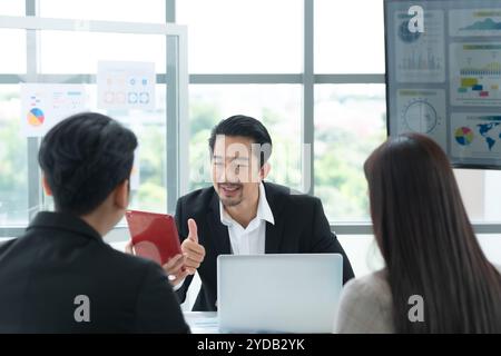 Eine Gruppe junger asiatischer Unternehmer. Das oberste Management trifft sich, um die Anlagedaten des Teams in einem Besprechungsraum zu prüfen Stockfoto