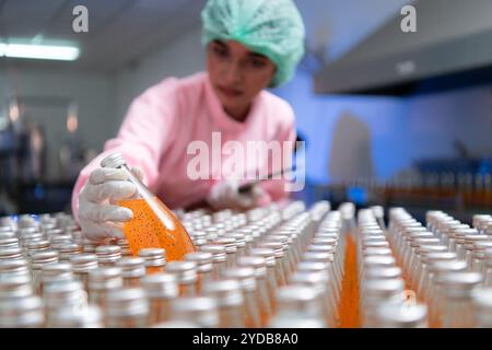 Die Mitarbeiter der Produktqualitätskontrolle an der Fruchtsaftproduktionslinie führen Produktqualitätsprüfungen durch, um sicherzustellen, dass die Produkte einwandfrei sind Stockfoto