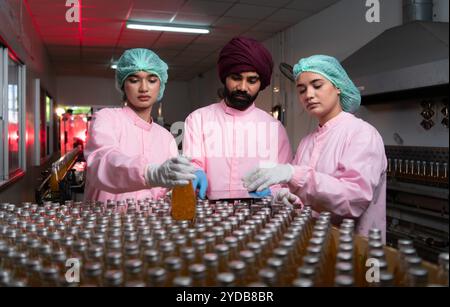 Die Mitarbeiter der Produktqualitätskontrolle an der Fruchtsaftproduktionslinie führen Produktqualitätsprüfungen durch, um sicherzustellen, dass die Produkte einwandfrei sind Stockfoto