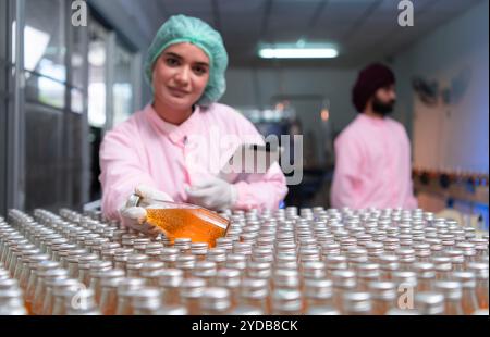 Die Mitarbeiter der Produktqualitätskontrolle an der Fruchtsaftproduktionslinie führen Produktqualitätsprüfungen durch, um sicherzustellen, dass die Produkte einwandfrei sind Stockfoto