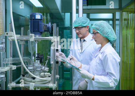 Wissenschaftler und Assistenten sind im Maschinenraum, um Öl und Cannabissamen zu extrahieren. Überprüfung des Cannabisölextraktors vor St. Stockfoto