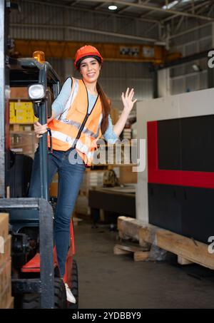 Porträt einer asiatischen Frau mit einem Gabelstapler, mit dem schwere Gegenstände in einem Lagerhaus angehoben werden. Stockfoto