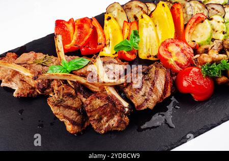 Gegrillte Lammkoteletts mit Gemüse auf einem Steinbrett Stockfoto