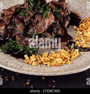 Rinderleber mit Zwiebelchips auf Teller Stockfoto