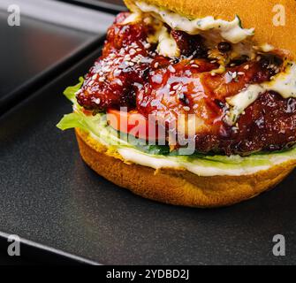 Appetitliche knusprige Hähnchenburger auf schwarzen Tellern Stockfoto