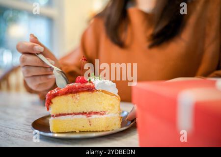 Glückliche asiatische Frau, die leckeren Weihnachtskuchen fruitÂ. Weihnachtsfeier mit köstlichem Stück Weihnachtskuchen Neujahr und Chri Stockfoto