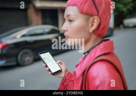 Traveler Gen z Mädchen Ledermode mit Punk asiatische Frau Tourist in der Stadt Straße Suche Standort in Karte Anwendung Online Smartphone mit GPS na Stockfoto