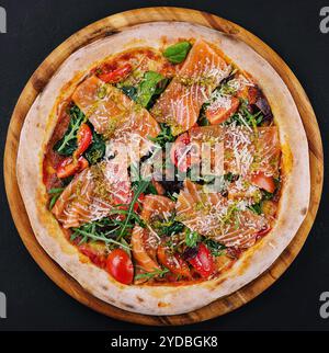 Köstliche heiße Pizza mit Lachs, Käse, Tomaten und Aradel Stockfoto