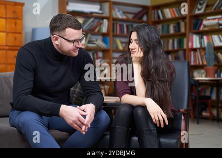 Lächelnde junge Frau besucht männlichen Therapeuten zur Sitzung Stockfoto