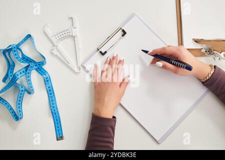 Ernährungsberater Arzt schriftlich Diät-Plan auf dem Tisch mit Maßband, Blick von oben Stockfoto
