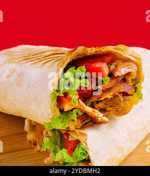 Shawarma mit Huhn, Tomaten und Salat auf einem Holzbrett Stockfoto