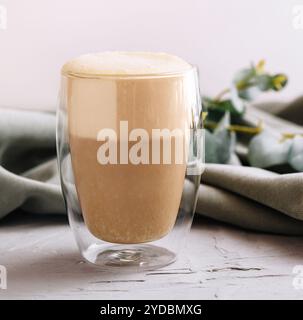 Hitzebeständiger doppelwandiger Glasbecher gefüllt mit Latte oder Cappuccino Stockfoto