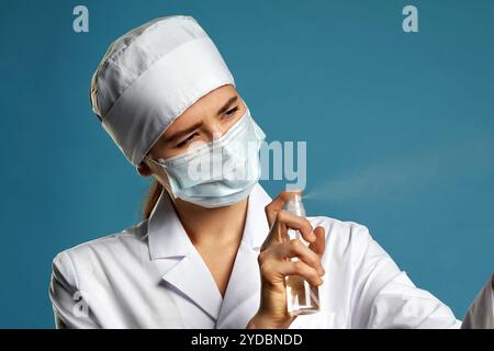 Junge Ärztin mit Spray antiseptischen Spray über blauem Hintergrund Stockfoto