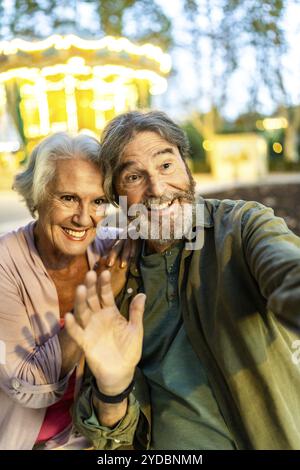 Vertikale Nahaufnahme aus der persönlichen Perspektive eines glücklichen modernen Seniorenpaares, das winkt und Selfie in der Stadt macht Stockfoto