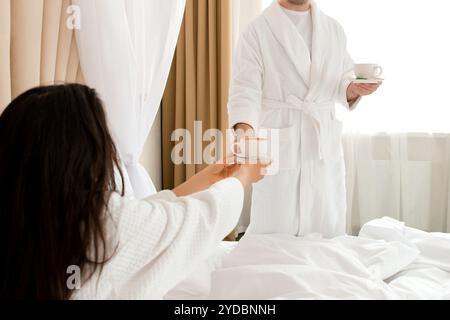 Mann, der seiner Freundin Kaffee bringt, die im Bett liegt Stockfoto