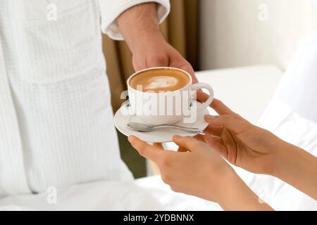 Nahaufnahme eines Mannes, der Kaffee zu seiner Freundin bringt, die lügt Im Bett Stockfoto