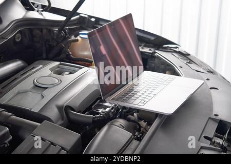 Laptop auf einem Auto in der Autowerkstatt, Automechaniker-Werkstatt-Konzept Stockfoto