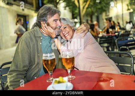 Seniorenpaar genießt Bier mit Tapa auf einer Stadterrasse Stockfoto