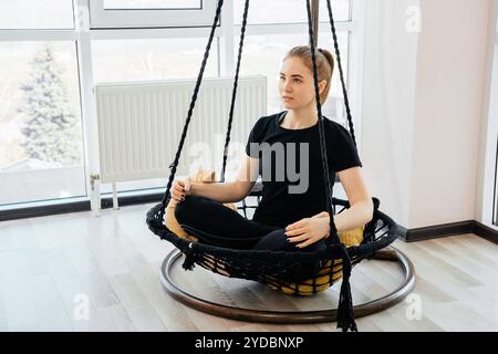 Junges Mädchen tun Yoga Pose sitzen auf einem Schaukel in Yoga-Kurs Stockfoto