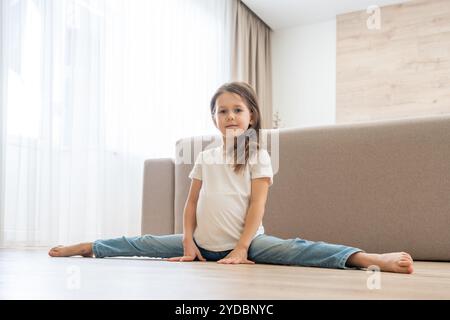 Kleines Mädchen tun Split im Wohnzimmer zu Hause Stockfoto