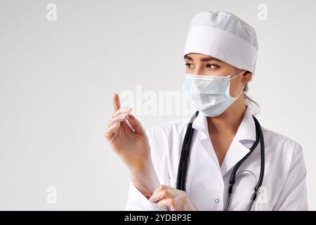 Junger Arzt, der chirurgische Handschuhe über weißem Hintergrund aufsetzt Stockfoto