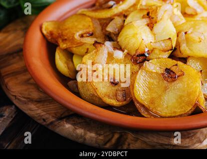 Gebratene Kartoffeln mit Zwiebeln auf Holztablett Stockfoto