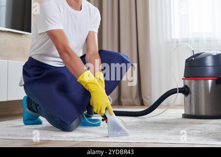 Mann Reinigung Teppich Im Wohnzimmer Mit Staubsauger Zu Hause. Reinigungsdienstkonzept Stockfoto