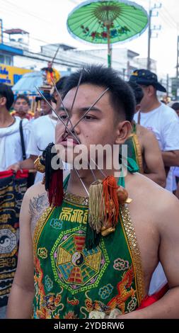 Ein Gläubiger läuft in einer Prozession, nachdem er während des jährlichen Vegetarian Festival in Phuket Town am Baan Tha Rua Schrein durchbohrt wurde. Das Festival brachte 15 Milliarden Thai Baht in die lokale Wirtschaft mit über 400.000 Besuchern ein. Stockfoto