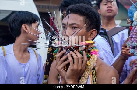 Ein Gläubiger läuft in einer Prozession, nachdem er während des jährlichen Vegetarian Festival in Phuket Town am Baan Tha Rua Schrein durchbohrt wurde. Das Festival brachte 15 Milliarden Thai Baht in die lokale Wirtschaft mit über 400.000 Besuchern ein. Stockfoto