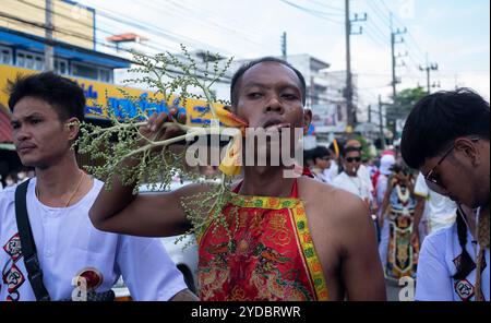 Ein Gläubiger läuft in einer Prozession, nachdem er während des jährlichen Vegetarian Festival in Phuket Town am Baan Tha Rua Schrein durchbohrt wurde. Das Festival brachte 15 Milliarden Thai Baht in die lokale Wirtschaft mit über 400.000 Besuchern ein. Stockfoto