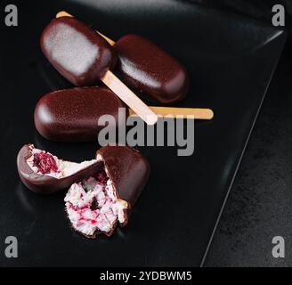 Eis-Dessert mit Kirschen auf schwarzem Teller Stockfoto