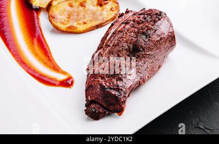 Appetitliches gebratenes Schweinefleisch mit Kartoffeln auf Teller Stockfoto