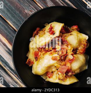 Gebackene Kartoffelknödel mit gebratenem Speck und Zwiebeln Stockfoto