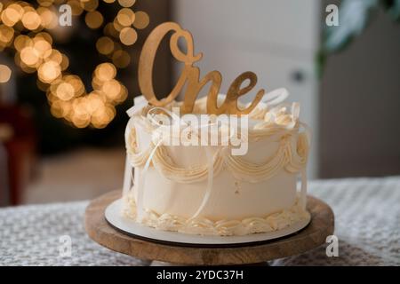 Eleganter Kuchen zum ersten Geburtstag mit dekorativem One Topper und weichem Creme-Frosting. Stockfoto