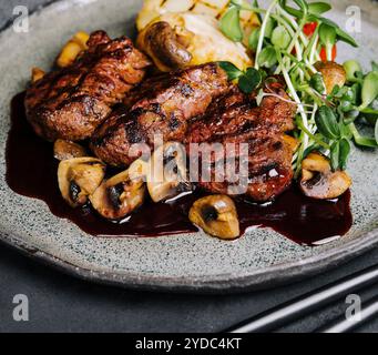 Seltene gebratene, dicke, saftige Rinderfilet-Medaillons, garniert mit geschmorten Pilzen und mit frischen Kräutern abgeschmeckt Stockfoto