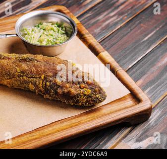 Gebratener Fisch auf Holzbrett mit scharfer Sauce Stockfoto