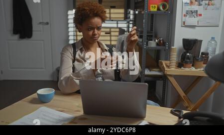 afroamerikanische Detektivin analysiert Beweise im Polizeirevier. Stockfoto