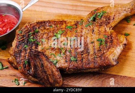 Gegrilltes knuspriges Hähnchenschenkelviertel auf dem Holzbrett Stockfoto