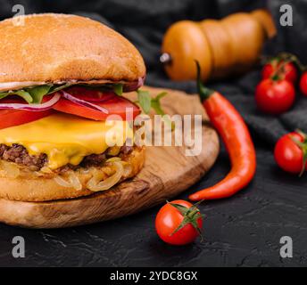 Leckerer gegrillter, hausgemachter Burger mit Rindfleisch, Tomaten, Käse, Zwiebeln und Salat Stockfoto