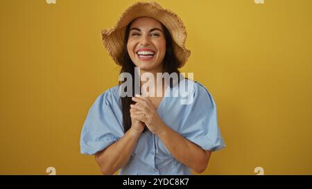 Schöne Frau lächelt über einem isolierten gelben Hintergrund mit Hut und blauer Bluse Stockfoto