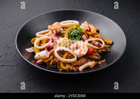 Thailändischer, scharfer Salat mit Meeresfrüchten auf schwarzem Teller Stockfoto