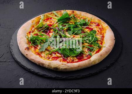 Pizza mit Rucola auf schwarzem Brett Stockfoto
