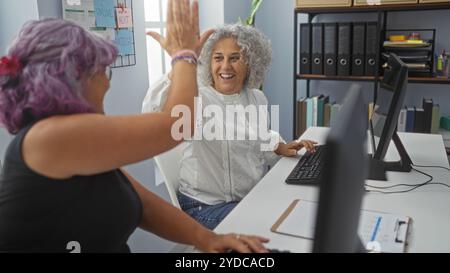 Frauen, die in einem Büro High-Five sind, bedeuten Teamarbeit und Erfolg Stockfoto