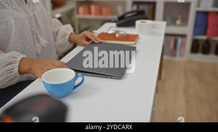 Frau Hände arbeiten in einem Wohnhaus Innenraum und legen einen Laptop auf einen Schreibtisch mit einer Tasse Kaffee in der Nähe Stockfoto