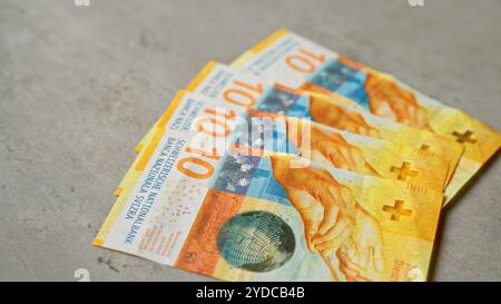 Schweizer Banknoten mit 10-Franken-Stückelungen auf einer Betonoberfläche sind in einem ordentlichen Stapel angeordnet, der lebendige Farben und Designdetails hervorhebt. Stockfoto