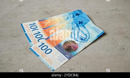 Schweizer 100-Franken-Banknoten auf einer Betonoberfläche mit leuchtenden Farben und komplizierten Designs, die die in der schweiz verwendete Währung hervorheben. Stockfoto