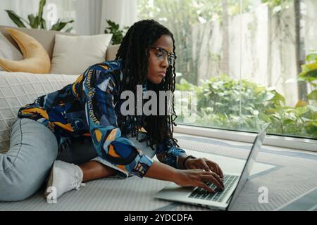 Junge Frau, Die Sich Entspannt, Während Sie In Innenräumen Mit Dem Laptop Arbeitet Stockfoto