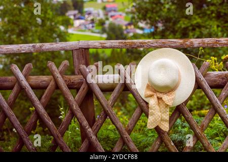 Weibliche Sommerhut hängt am hölzernen rustikalen Zaun Stockfoto