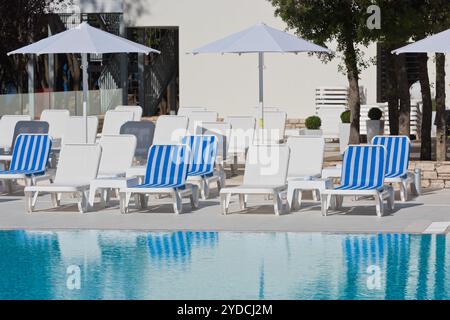 Sonnenliegen und Sonnenschirme am Pool an einem sonnigen Tag Stockfoto